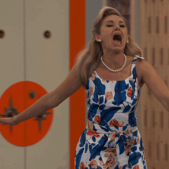 a woman in a blue and white floral dress is screaming with her mouth open