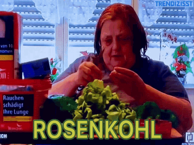 a woman is sitting at a table with a box of rosenkohl cigarettes