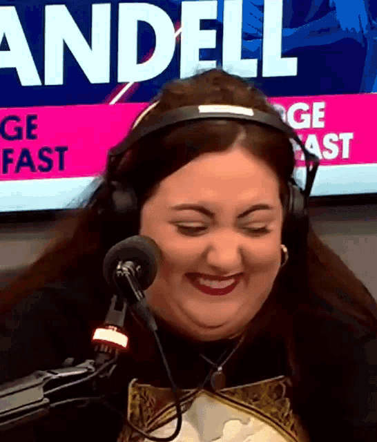 a woman wearing headphones smiles in front of a sign that says " andell "