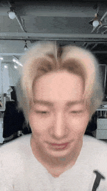 a man with blonde hair is making a funny face in a room with a white shirt on .