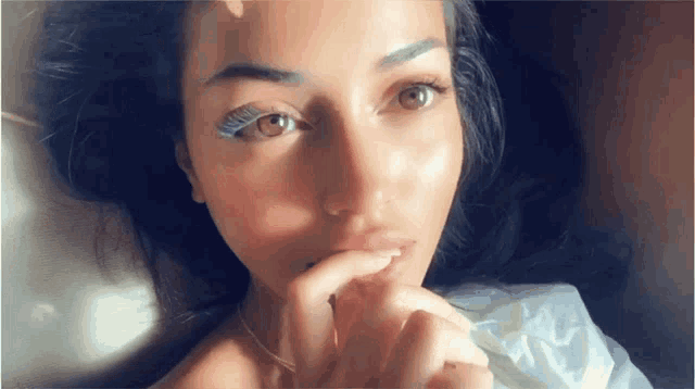 a close up of a woman laying down with her hand on her mouth