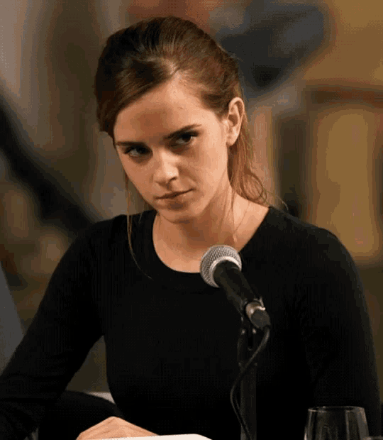 a woman sitting in front of a microphone looking at something
