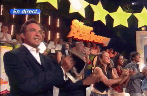 a group of people are applauding in front of a sign that says en direct