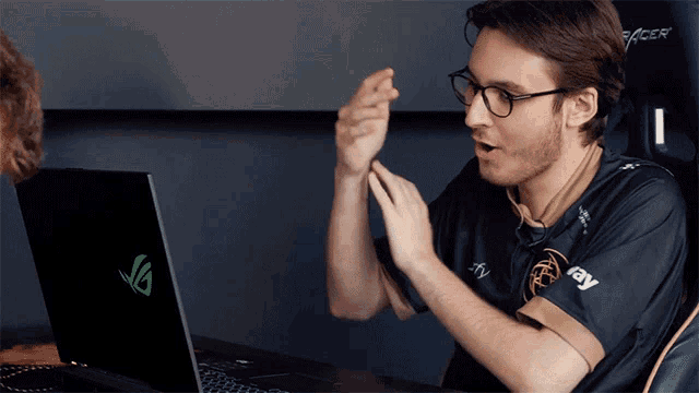 a man sitting in front of a laptop that has a green g on the screen