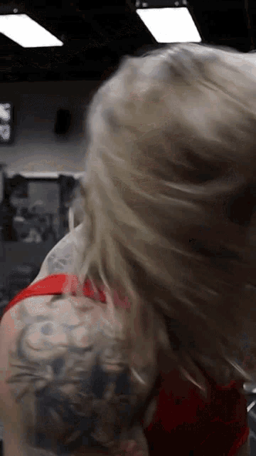 a woman with a tattoo on her shoulder is standing in a gym