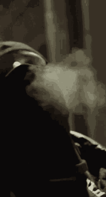 a close up of a person smoking a cigarette with smoke coming out of it