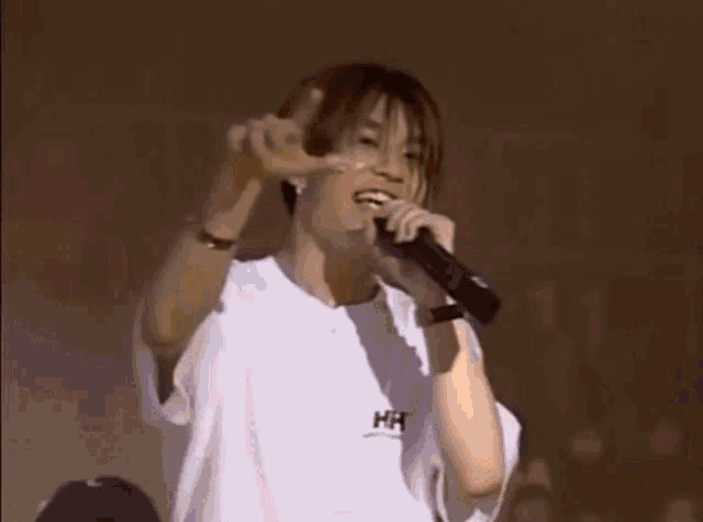 a young man in a white shirt is singing into a microphone .