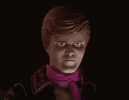 a doll with a purple scarf around his neck is looking at the camera