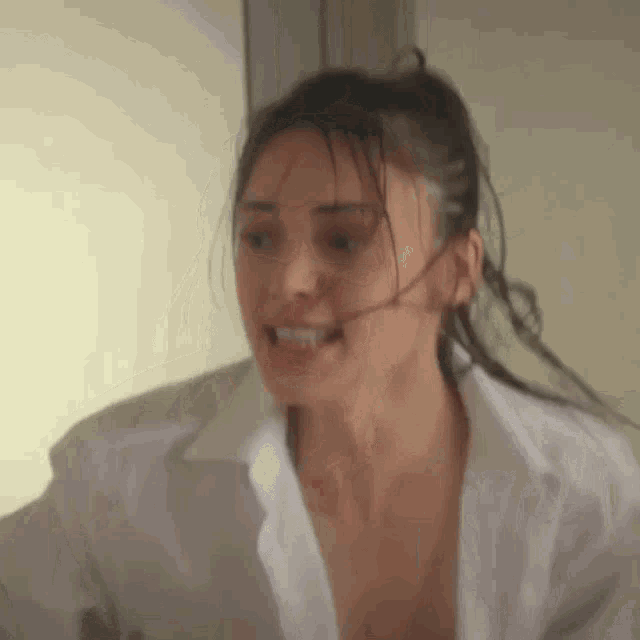a woman in a white shirt is making a funny face while standing in a room .