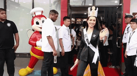 a woman wearing a sash that says vietnam stands in front of a jollibee mascot