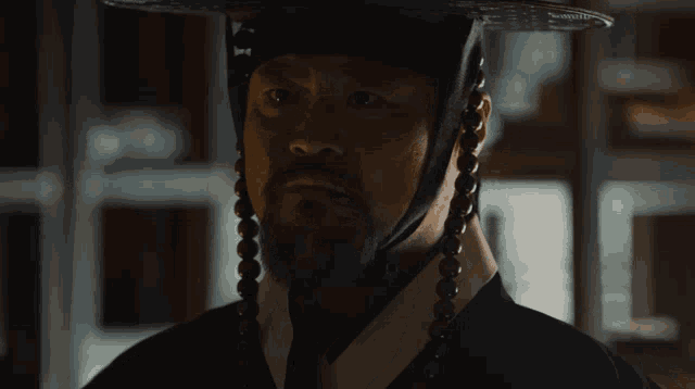 a man with a beard wearing a hat and tie