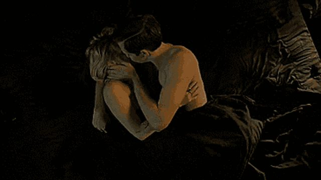 a man and a woman are laying on a bed and kissing