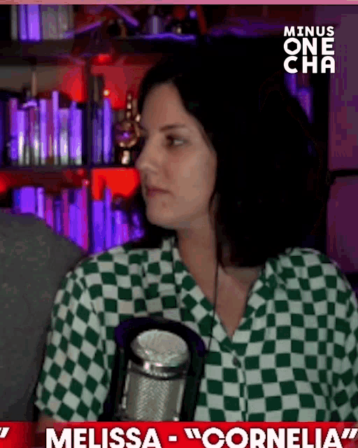 a woman in a green and white checkered shirt is holding a microphone