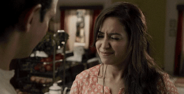 a woman is making a funny face in front of a man .