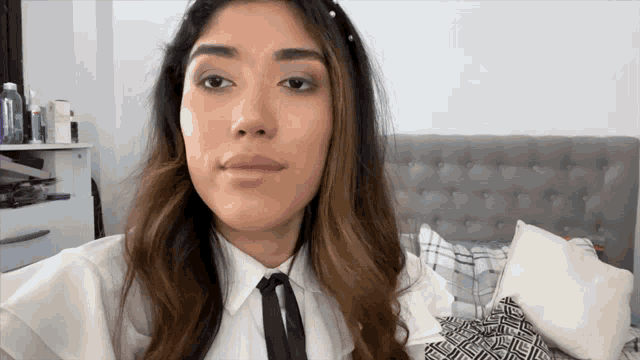 a woman wearing a white shirt and a black tie looks at the camera