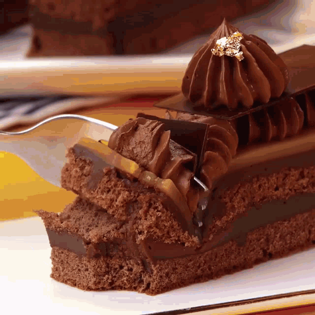 a slice of chocolate cake with a gold leaf on top