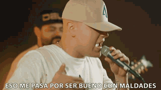 a man singing into a microphone with the words " eso me pasa por ser bueno con maldades " below him