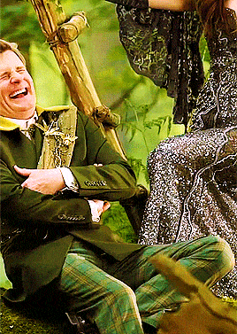a man in a green suit is laughing while sitting next to a woman in a dress