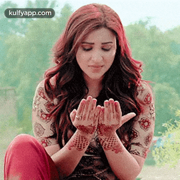 a woman with henna on her hands is sitting down with her legs crossed .
