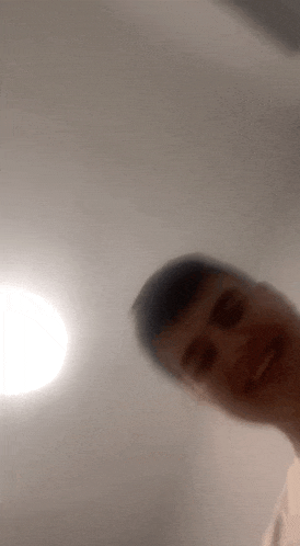 a blurry picture of a man taking a selfie with a light behind him .