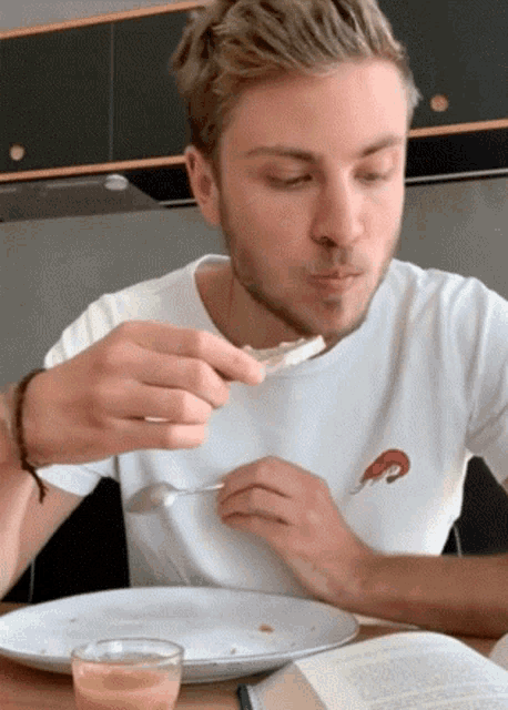 a man wearing a white shirt with a shrimp on it is eating food