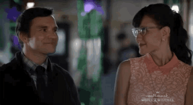 a man and a woman are looking at each other and the man is wearing glasses .