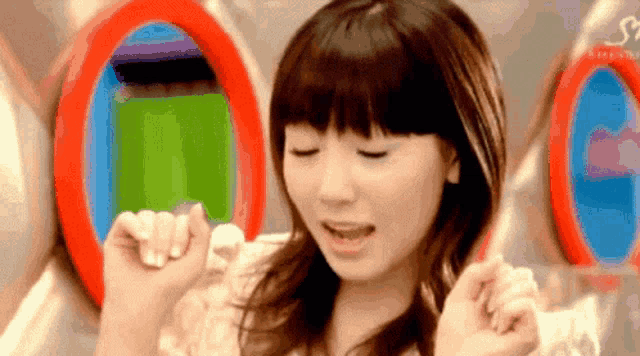 a woman is standing in front of a mirror with her eyes closed and her hands in the air