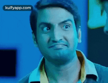 a man is making a funny face with his eyes closed in a dark room .