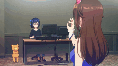 a woman sitting at a desk with a computer and a teddy bear next to her