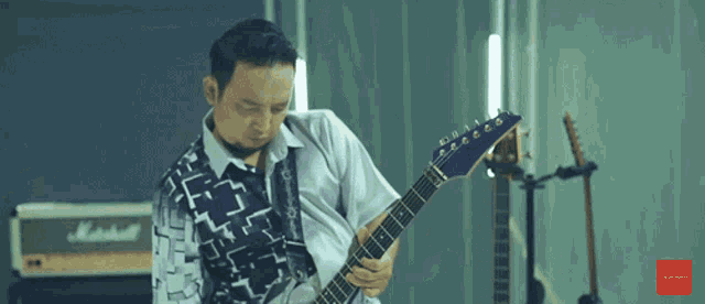 a man playing a guitar with a marshall amp in the background