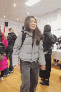 a girl in a grey jacket is dancing in a crowd of people