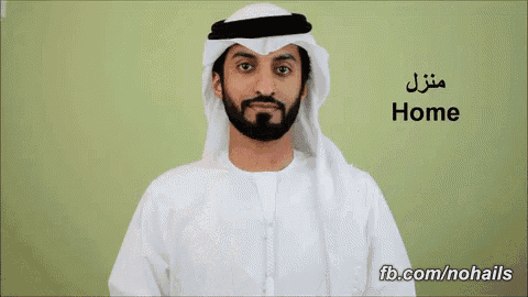 a man with a beard is wearing a white shirt and a white head scarf with the word home written on it