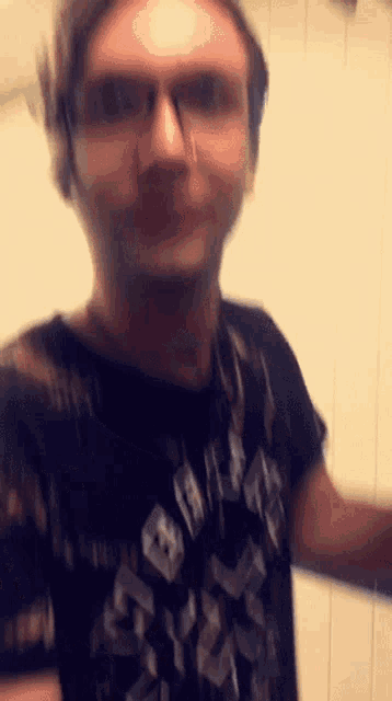 a blurry photo of a man wearing glasses and a black shirt that says ' slayer ' on it