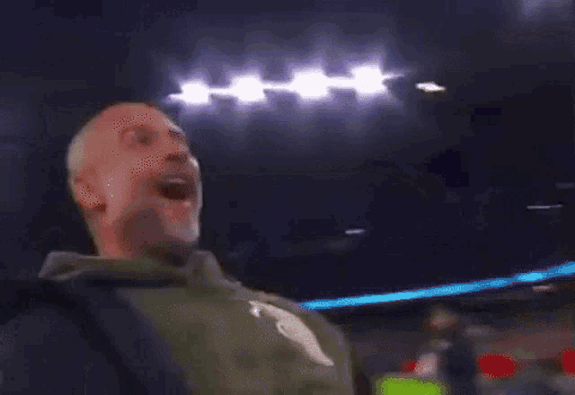 a man wearing a nike sweatshirt is screaming in a dark room