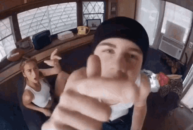 a man and woman are sitting on a couch and the man is pointing at the camera .