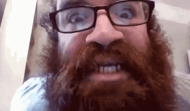 a man with a beard and glasses is smiling .