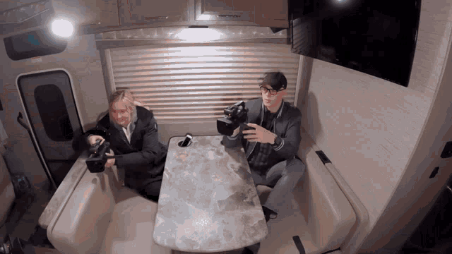 a man and woman are sitting at a table in a rv