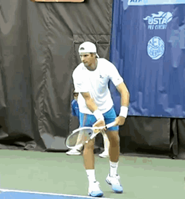 a man is holding a tennis racquet on a tennis court in front of a sign that says usta