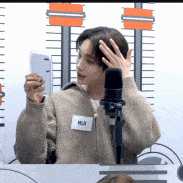 a man with a name tag that says rui looks at himself in a mirror