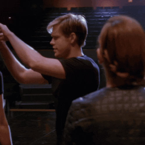 a man in a black shirt is dancing with a woman in a black leather jacket