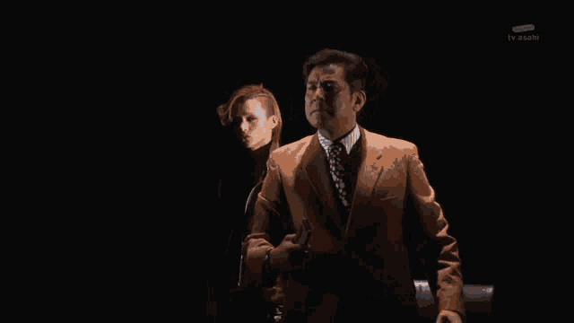 a man in an orange suit and tie is standing next to a woman in a black dress ..