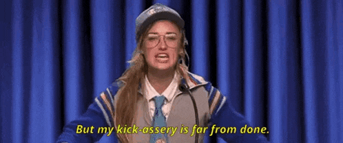 a woman is standing in front of a microphone and saying `` but my kick-assery is far from done . ''
