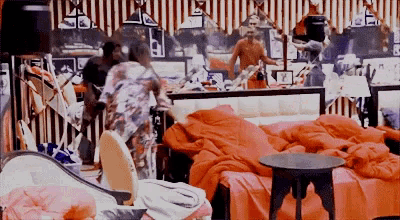a man is standing in front of a mirror in a room with red blankets