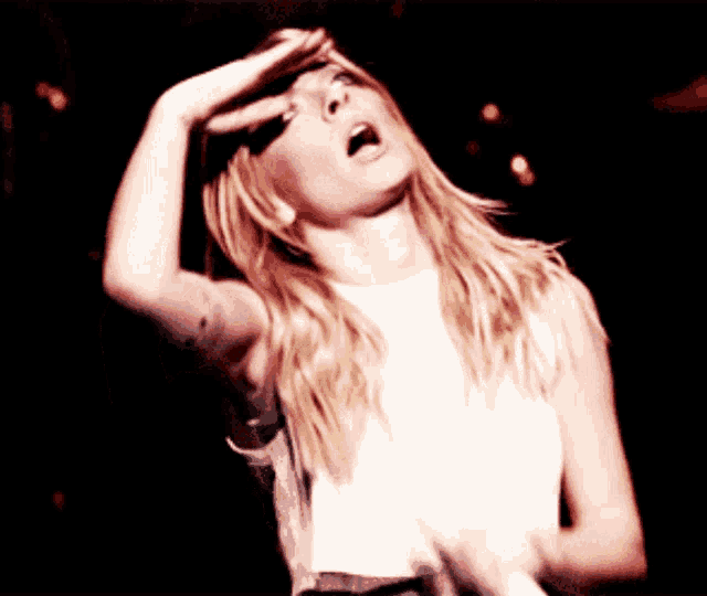 a woman covering her face with her hand while dancing