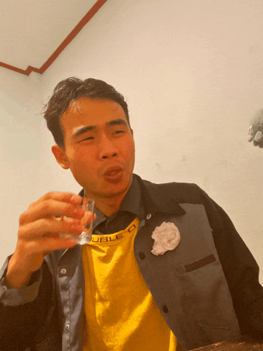 a man wearing a yellow shirt that says double o is holding a shot glass