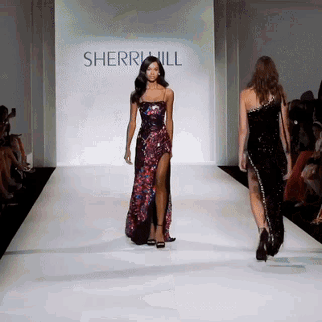 two models walk down the runway at a sherri hill show