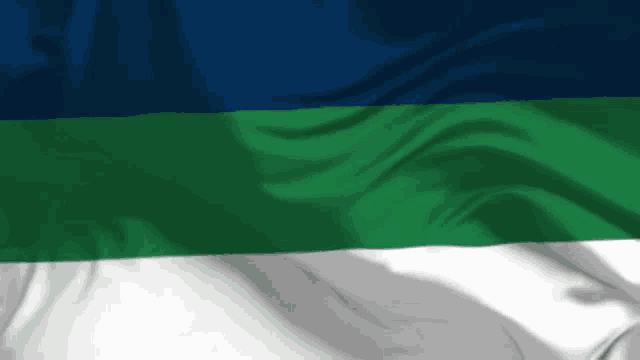 a blue green and white flag is being blown in the wind