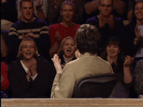a man sitting in front of a crowd clapping