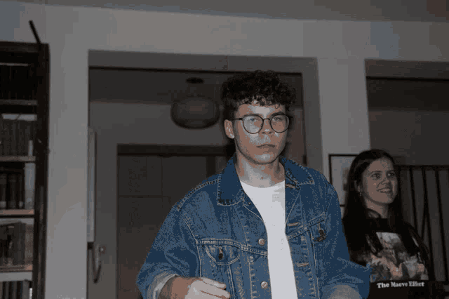a man in a denim jacket is standing next to a woman wearing a black shirt that says the havoc killer
