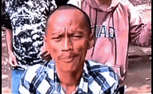 a man with a beard and a plaid shirt is making a funny face .